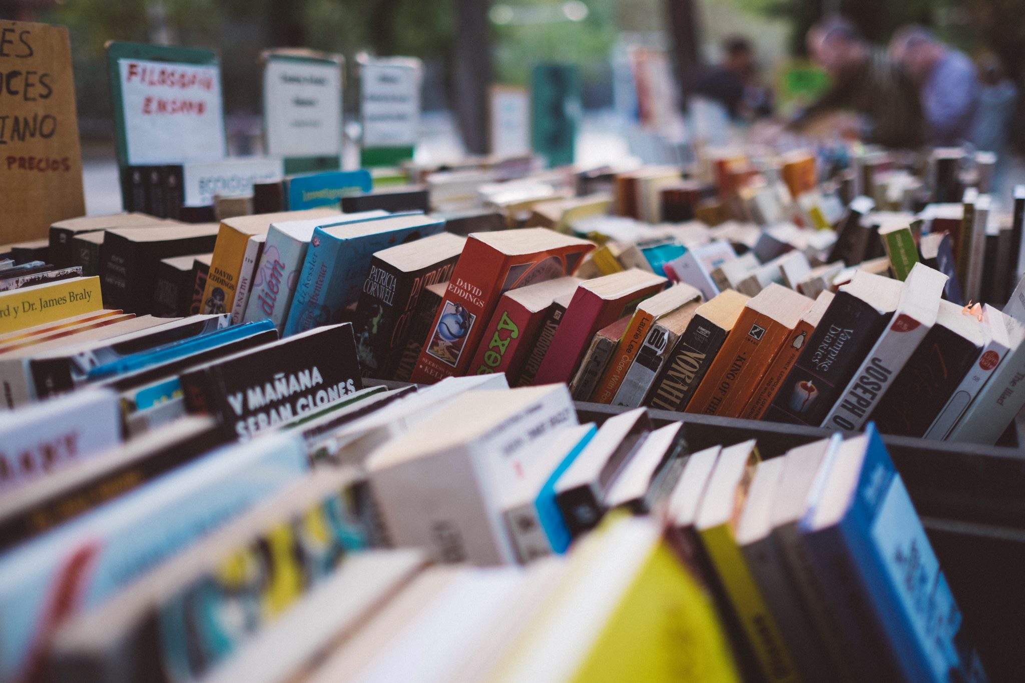 Rows and rows of books in bins for browsing. The books are all different colours and sizes. There are signs at the top of each row with out-of-focus text.